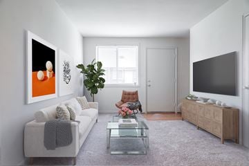Baltimore apartment for rent - A modern living room with a grey sofa, a glass coffee table, a wooden cabinet, and a large painting on the wall.