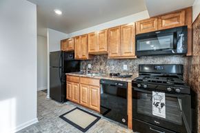 Baltimore apartment for rent - A kitchen with black appliances and wooden cabinets.