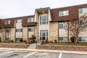 Baltimore apartment for rent - A building with a brown roof and tan walls with a parking lot in front.