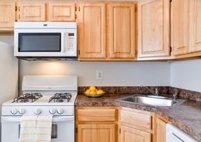 Baltimore apartment for rent - A kitchen with a white stove and a white microwave above it.