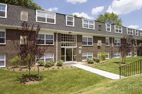 Baltimore apartment for rent - A brick building with a black fence in front.