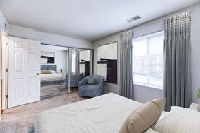 Glen Burnie apartment for rent - A bedroom with a large bed and a grey chair.
