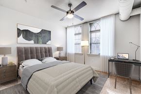 Baltimore apartment for rent - A bedroom with a large bed, a desk, and a ceiling fan.