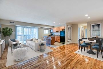 Baltimore apartment for rent - A spacious living room with a white sofa set and wooden flooring.