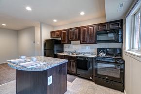 Baltimore apartment for rent - A kitchen with dark wood cabinets and black appliances.