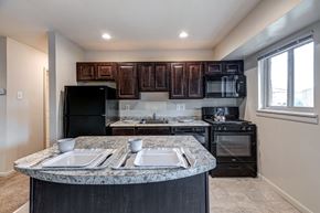 Baltimore apartment for rent - A kitchen with black appliances and brown wooden cabinets.