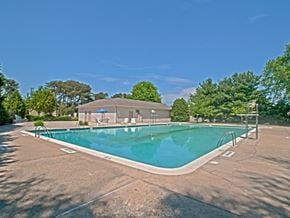 Glen Burnie apartment for rent - A swimming pool surrounded by a concrete patio and trees.