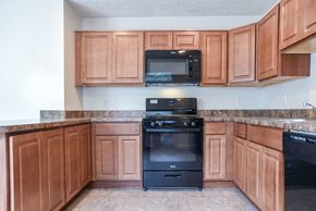 Glen Burnie apartment for rent - A kitchen with wooden cabinets and a black stove.