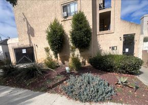 Long Beach apartment for rent - A house with a brown wall and a green bush in front.