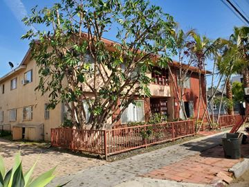 Long Beach apartment for rent - A house with a red fence and a tree in front.