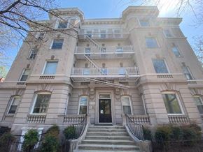 Washington apartment for rent - A large, two-story building with a black door and stairs leading up to it.
