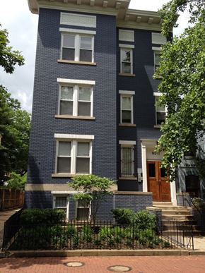 Washington apartment for rent - A blue brick building with a black iron fence in front.