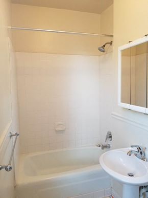 Washington apartment for rent - A white bathroom with a tub, sink and mirror.