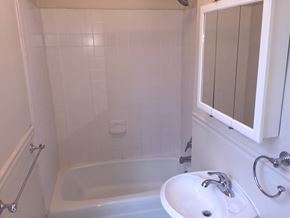 Washington apartment for rent - A white bathroom with a tub, sink and mirror.