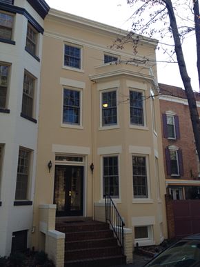 Washington apartment for rent - A white and yellow building with a black door and steps leading up to it.