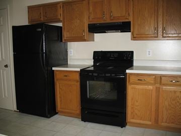 Vienna apartment for rent - A black refrigerator and oven in a kitchen with wooden cabinets.