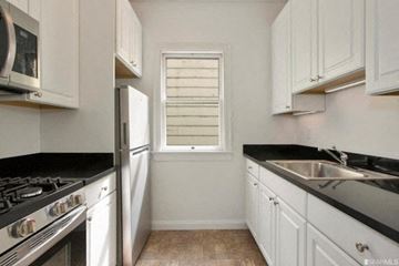 San Francisco apartment for rent - A kitchen with white cabinets and black countertops.