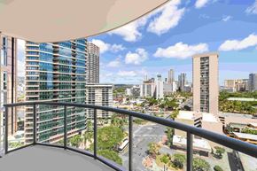 Honolulu apartment for rent - A balcony overlooks a cityscape with tall buildings and a clear sky.