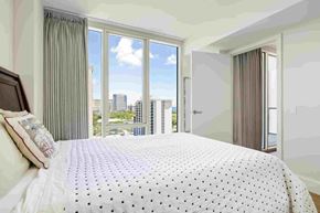Honolulu apartment for rent - A bedroom with a large bed and a view of the city.