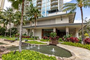 Honolulu apartment for rent - A building with a pool and fountain in front of it.