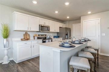 Waukee apartment for rent - A kitchen with white cabinets and a large island with four stools.