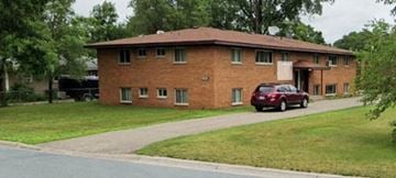 Fridley apartment for rent - A red car is parked in front of a brick house.