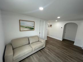 Lakeland apartment for rent - A beige couch sits in a room with a painting on the wall and a white door.