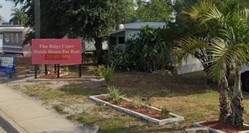 Pinellas Park apartment for rent - A sign for Pine Ridge Court Mobile Homes For Rent stands in front of a house.