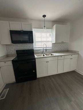 Fayetteville apartment for rent - an empty kitchen with white cabinets and black appliances