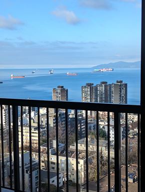 Vancouver apartment for rent - A view from a balcony looking out at a cityscape and ships in the water.