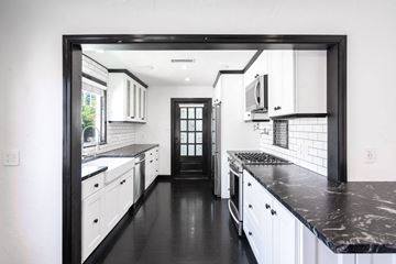 North Hollywood house for rent - a kitchen with white cabinets and black counter tops