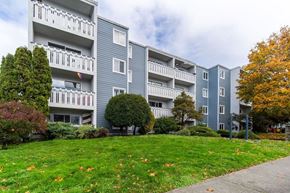 Victoria apartment for rent - Apartment building with green lawn and trees in front.