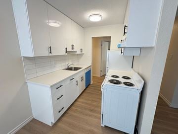 Victoria apartment for rent - A small kitchen with a white stove and cabinets.