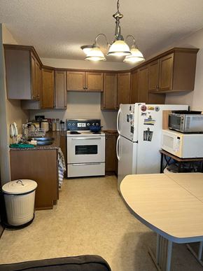 Calgary apartment for rent - a kitchen with white appliances and wooden cabinets and a table