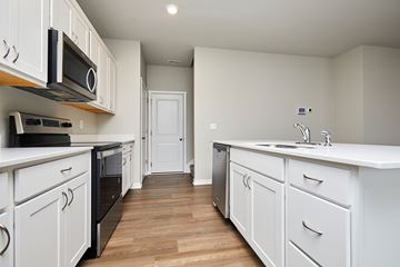 Urbandale apartment for rent - A kitchen with white cabinets and black appliances.