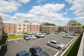 Newark apartment for rent - A parking lot with cars and apartment buildings in the background.