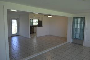 Cape Coral house for rent - an empty living room with a tile floor and a door to a kitchen
