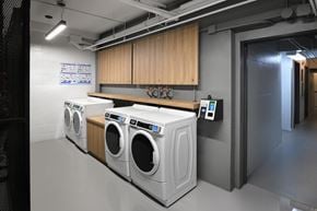 Ottawa apartment for rent - Three front loading washing machines are lined up in a laundry room.