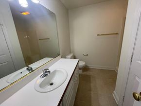 Wilson apartment for rent - A bathroom with a sink, mirror, toilet and a door.