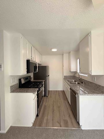 Long Beach apartment for rent - A kitchen with white cabinets and a granite countertop.