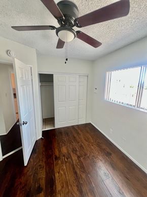 Long Beach apartment for rent - A room with a ceiling fan and wooden floors.