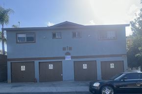 Long Beach apartment for rent - A black car is parked in front of a building with brown garage doors.