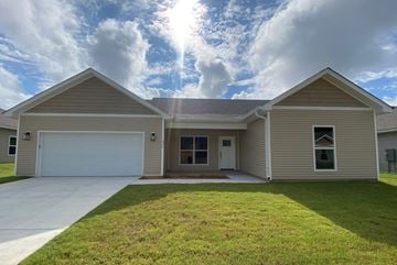 Benton house for rent - a beige house with a lawn in front of it