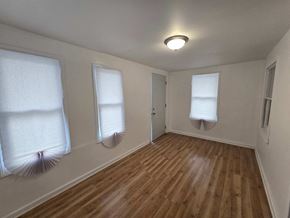 Gary house for rent - an empty living room with three windows and a wood floor