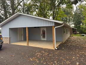Gray house for rent - a metal building with a garage and a driveway