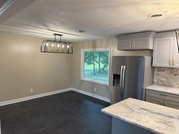 Gray house for rent - a kitchen with a island and a stainless steel refrigerator