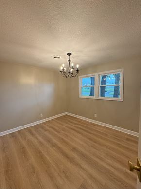Gray house for rent - an empty living room with wooden floors and a chandelier