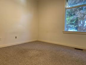 Victoria apartment for rent - A room with a carpeted floor and a window showing trees outside.