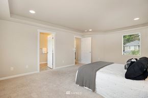 Seattle house for rent - A bedroom with a large bed and a window with a view of a house.