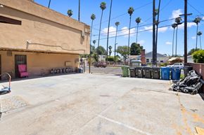 Los Angeles apartment for rent - A large, empty parking lot with a building to the left and a row of palm trees in the background.